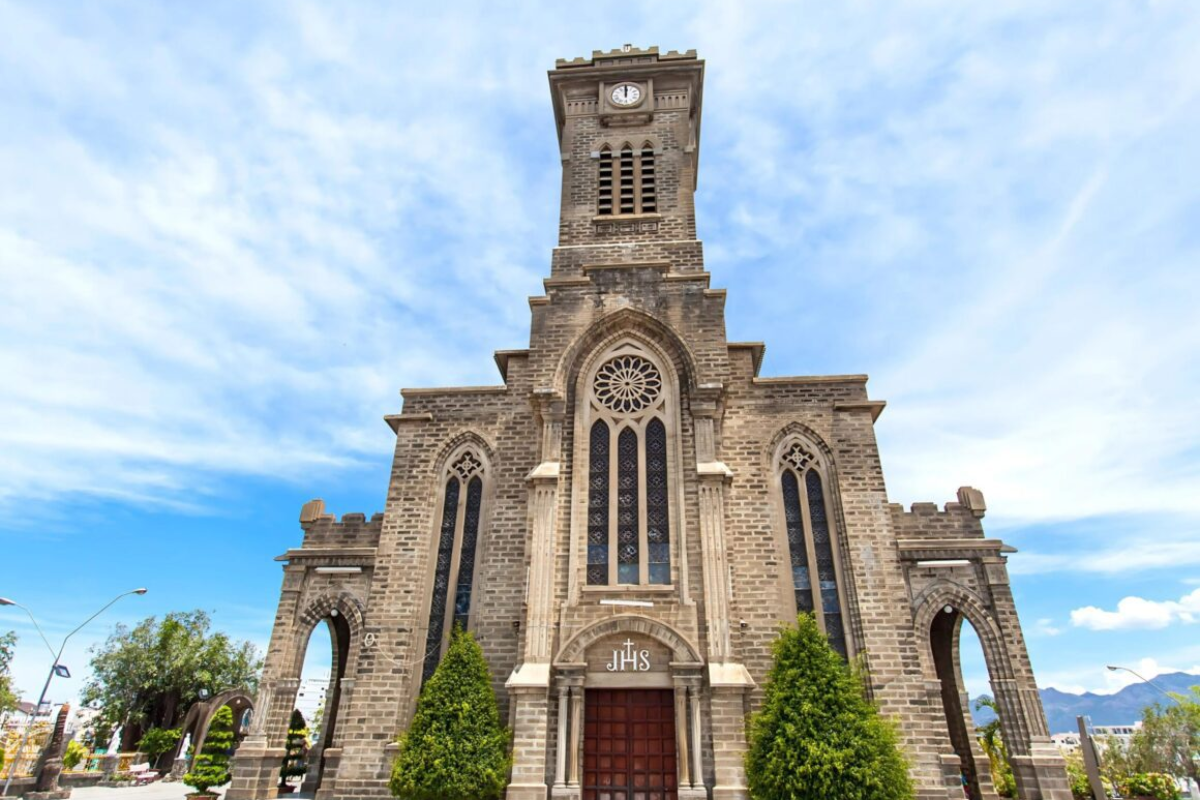 Nha Trang Stone Church with Gothic arches and bell tower in warm sunlight